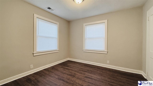 spare room featuring dark hardwood / wood-style floors and a textured ceiling