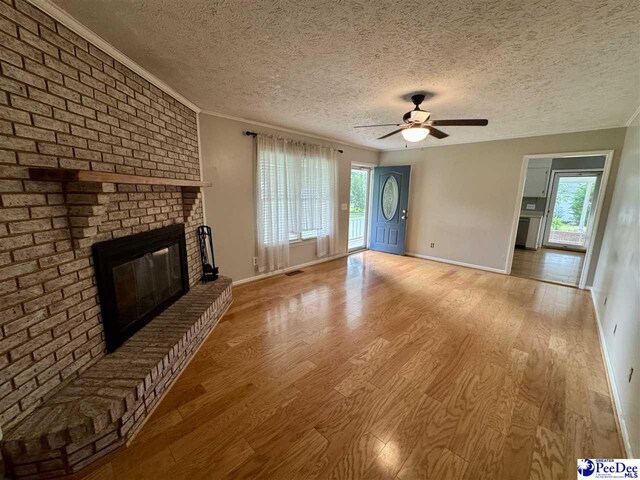 188 Chatham Trace Cir, Cheraw, SC 29520 - unfurnished living room with wood finished floors, plenty of natural light, a ceiling fan, a brick fireplace, and a textured ceiling