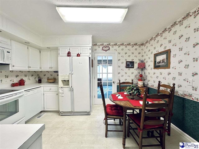 kitchen featuring white cabinetry, white appliances, and a textured ceiling