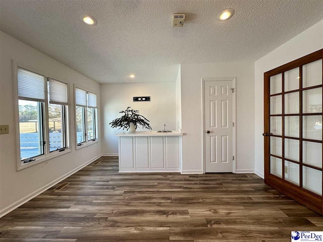 unfurnished room with dark wood-type flooring and a textured ceiling