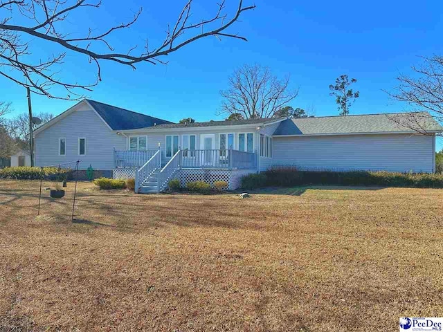 single story home with a wooden deck and a front lawn