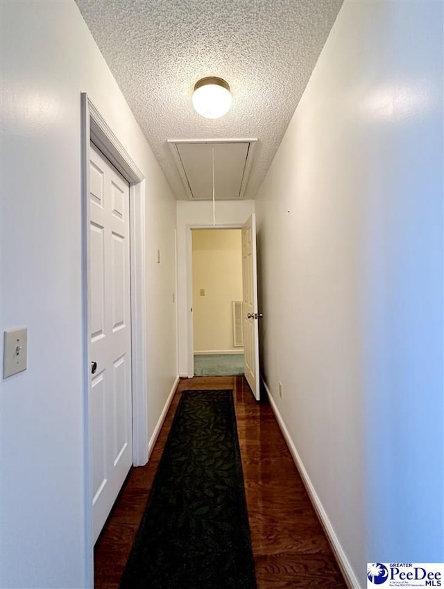 corridor with dark hardwood / wood-style floors and a textured ceiling