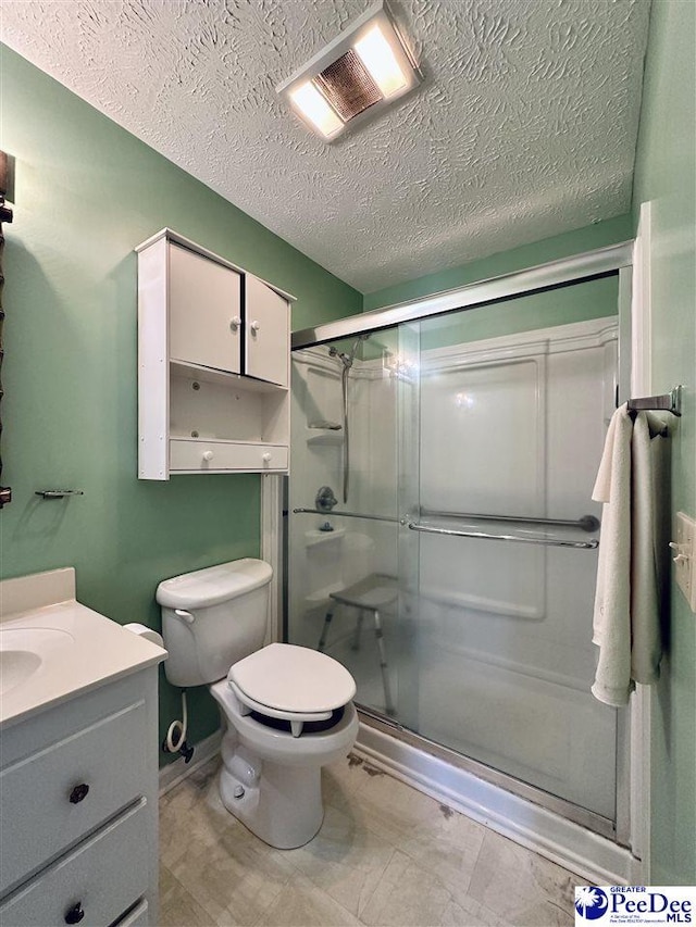 bathroom featuring vanity, toilet, a textured ceiling, and a shower with shower door