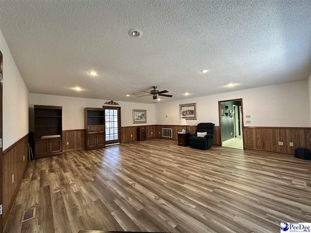 unfurnished living room with ceiling fan, wood-type flooring, and a textured ceiling