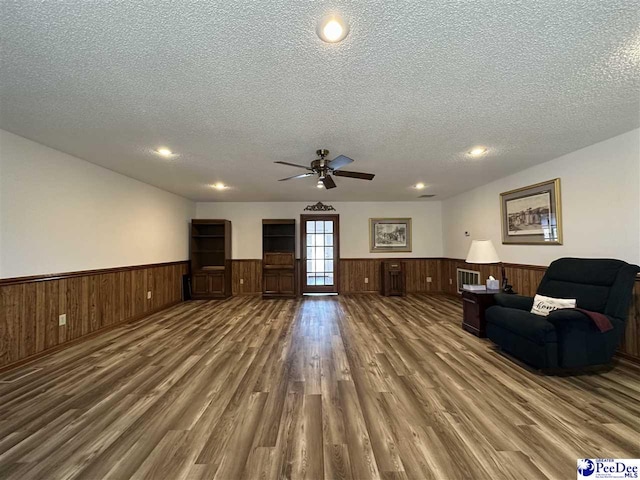 unfurnished living room with dark wood-type flooring, ceiling fan, and a textured ceiling