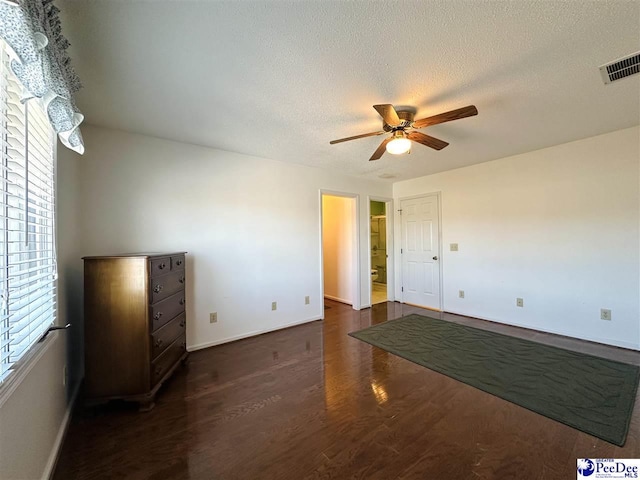 empty room with ceiling fan, dark hardwood / wood-style floors, and a textured ceiling