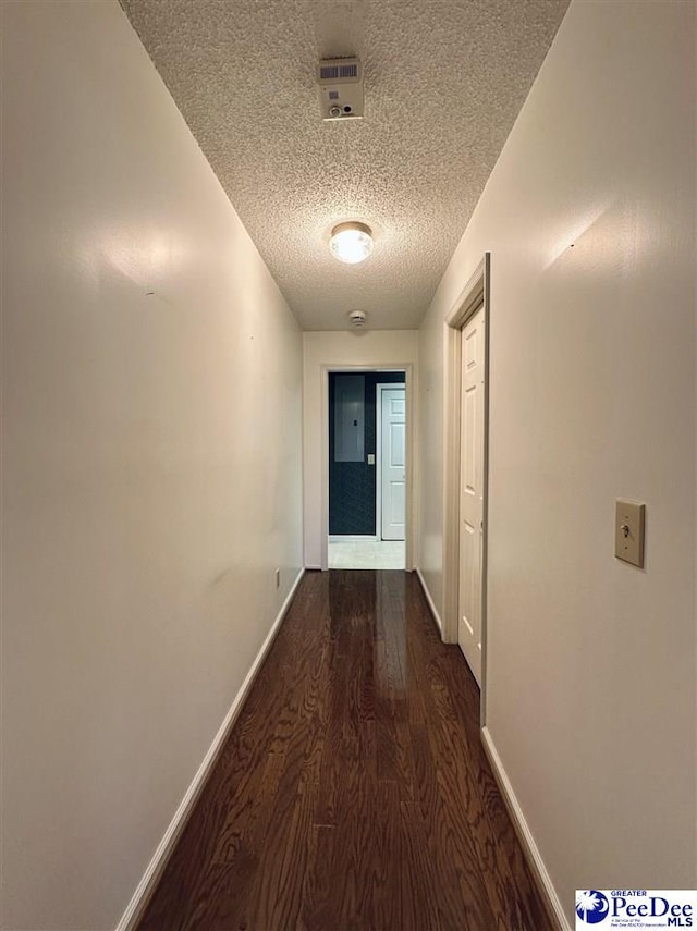 hallway featuring dark hardwood / wood-style floors and a textured ceiling