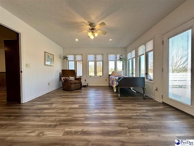 sitting room with ceiling fan, dark wood-type flooring, and a textured ceiling