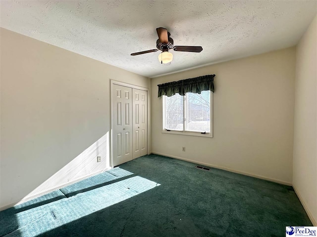 unfurnished bedroom featuring ceiling fan, a textured ceiling, a closet, and dark colored carpet