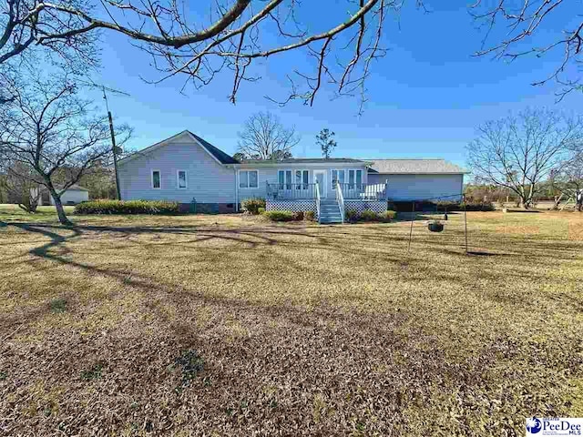 rear view of property featuring a wooden deck and a yard