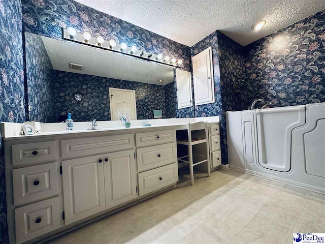 bathroom with vanity, a textured ceiling, and a tub