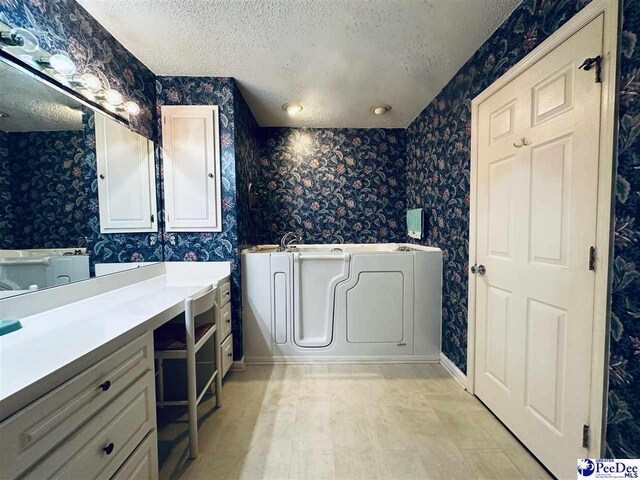 bathroom featuring vanity, a bath, and a textured ceiling