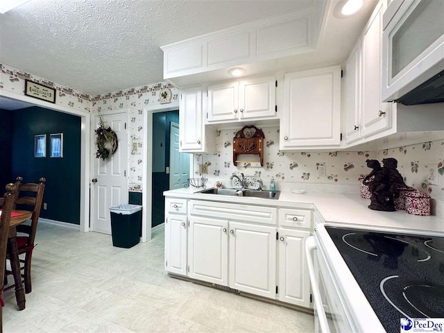 kitchen featuring electric stove, sink, a textured ceiling, and white cabinets