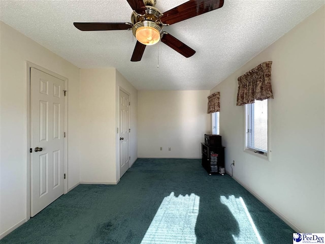 unfurnished bedroom with dark colored carpet, ceiling fan, and a textured ceiling