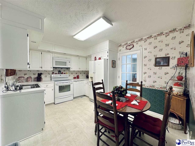 kitchen featuring white cabinetry, sink, white appliances, and a textured ceiling