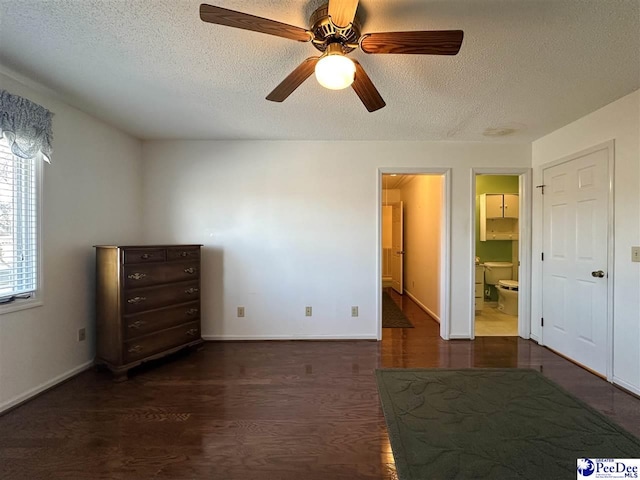 unfurnished bedroom with ceiling fan, ensuite bath, dark wood-type flooring, and a textured ceiling