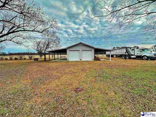 view of yard featuring an outbuilding, a carport, and a garage