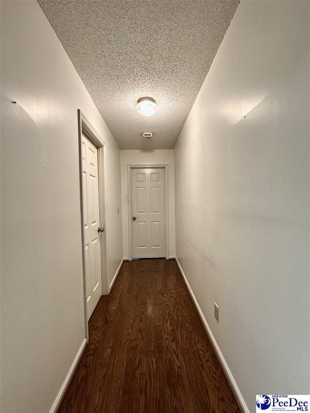 corridor with dark wood-type flooring and a textured ceiling