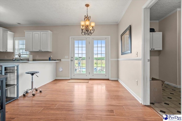 2770 Gray Dr, Darlington, SC 29532 - kitchen featuring light wood finished floors, a textured ceiling, a chandelier, white cabinets, and pendant lighting