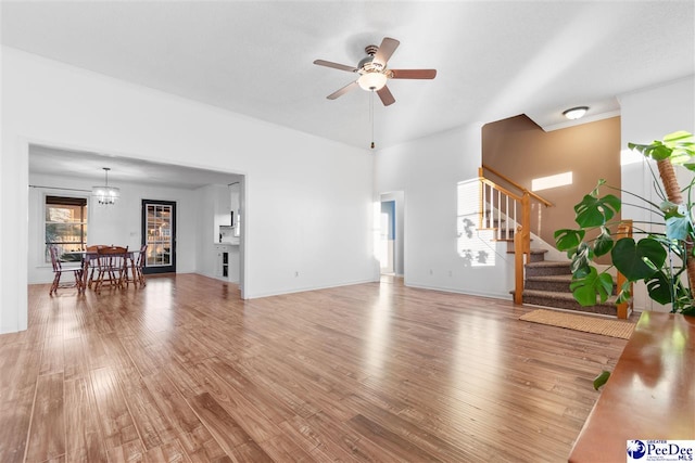 unfurnished living room featuring hardwood / wood-style floors and ceiling fan with notable chandelier