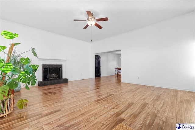 unfurnished living room with ceiling fan, a fireplace, and light hardwood / wood-style flooring