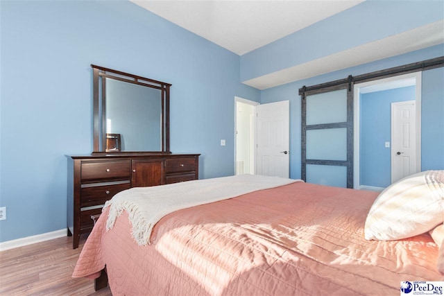 bedroom with wood-type flooring and a barn door