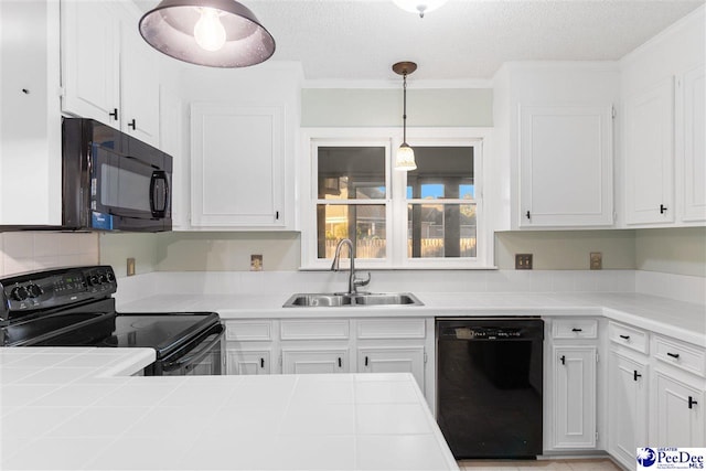 kitchen with sink, tile counters, black appliances, and hanging light fixtures