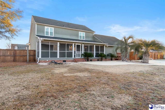 view of front facade with a front lawn, a sunroom, and a patio