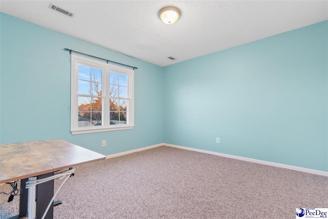 unfurnished office with carpet flooring and a textured ceiling