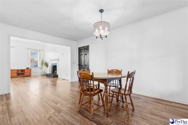 dining area featuring ornamental molding, hardwood / wood-style floors, a notable chandelier, and a textured ceiling