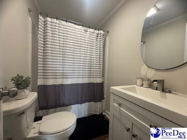 full bathroom featuring toilet, vanity, crown molding, and curtained shower