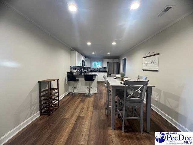 dining room with baseboards, visible vents, and dark wood-style floors