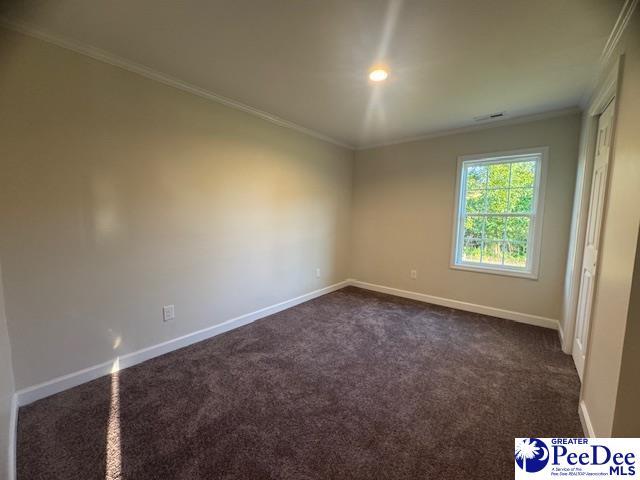 unfurnished room featuring dark carpet, baseboards, and ornamental molding