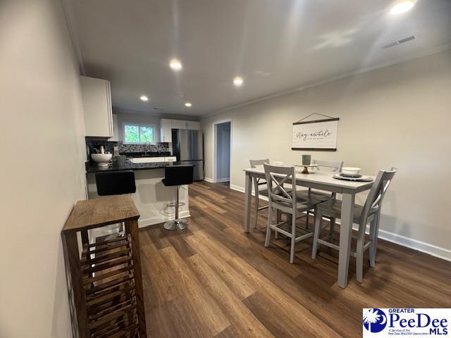 dining area featuring ornamental molding, visible vents, dark wood-style floors, and recessed lighting
