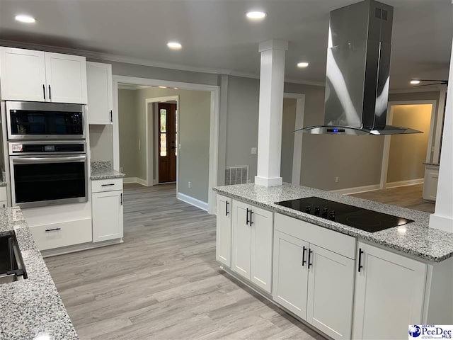 kitchen with crown molding, appliances with stainless steel finishes, white cabinetry, light stone counters, and island exhaust hood