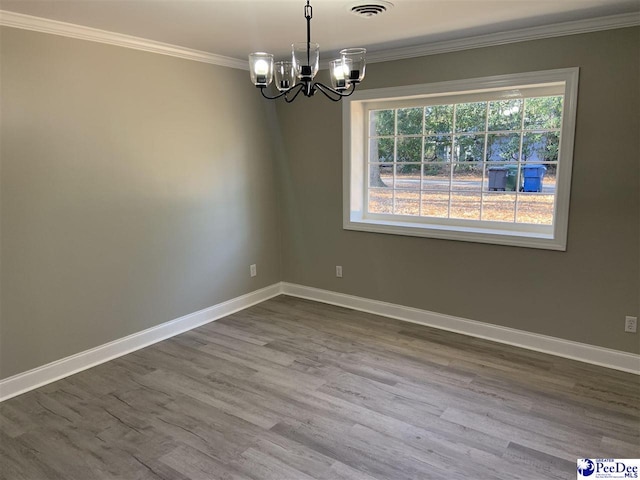 empty room featuring ornamental molding, wood-type flooring, and an inviting chandelier