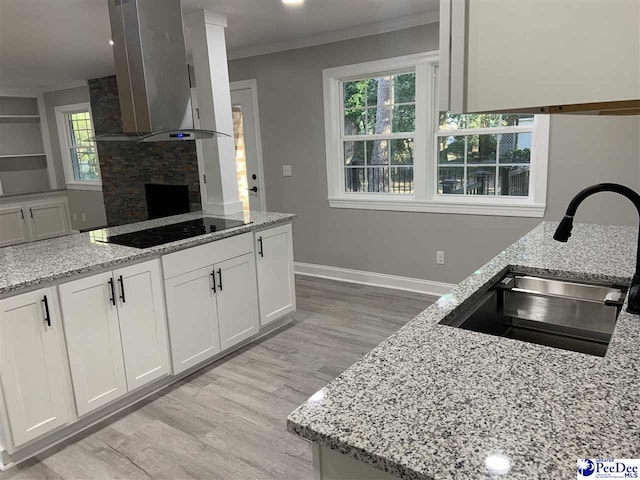 kitchen featuring island exhaust hood, sink, white cabinets, and light stone counters