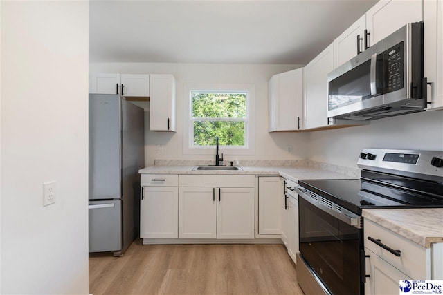 kitchen with light countertops, a sink, white cabinets, and stainless steel appliances