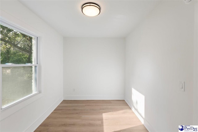 empty room featuring light wood-style floors, baseboards, and visible vents