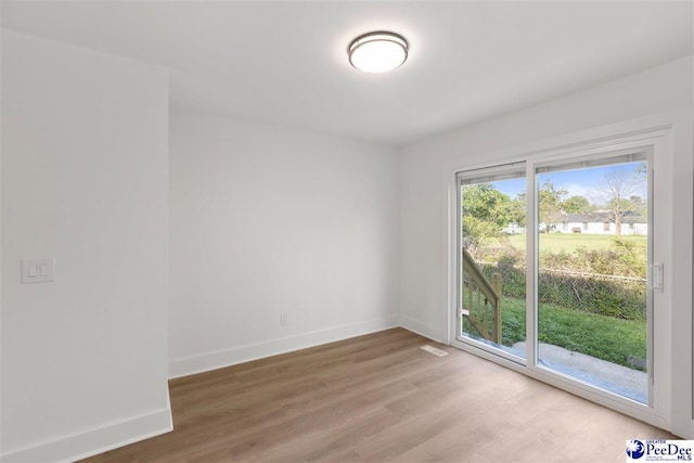 unfurnished room with visible vents, light wood-style flooring, and baseboards