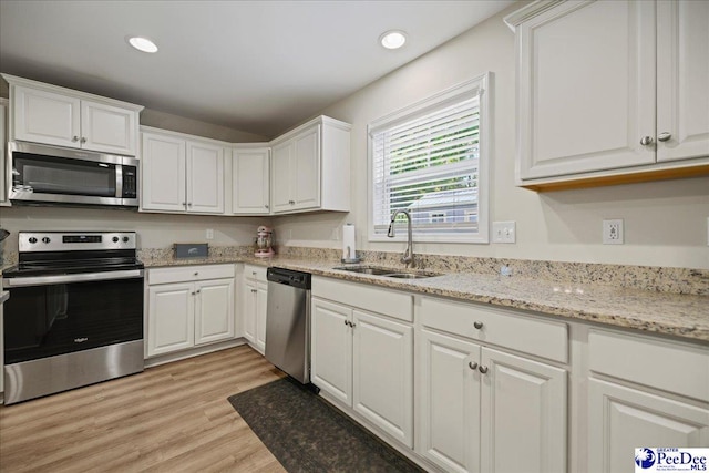 1757 Lake Wateree Dr, Florence, SC 29501 - kitchen with stainless steel appliances, white cabinets, light wood-style floors, recessed lighting, and light stone counters