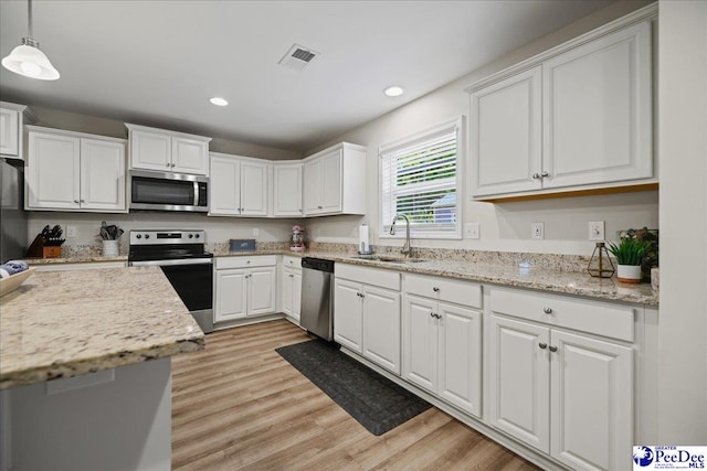 1757 Lake Wateree Dr, Florence, SC 29501 - kitchen featuring stainless steel appliances, white cabinets, light wood finished floors, recessed lighting, and pendant lighting