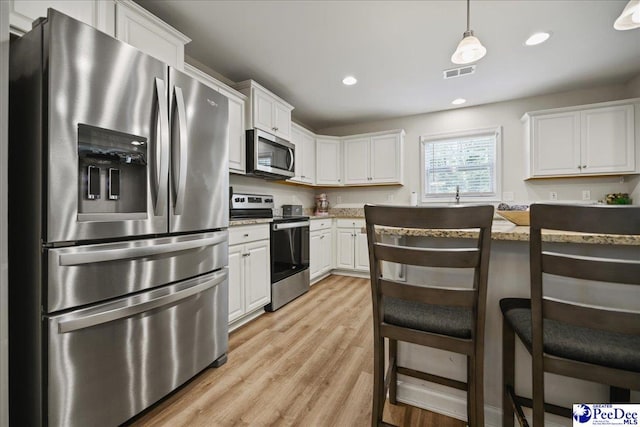 1757 Lake Wateree Dr, Florence, SC 29501 - kitchen with appliances with stainless steel finishes, white cabinetry, light wood-style floors, recessed lighting, and a kitchen breakfast bar