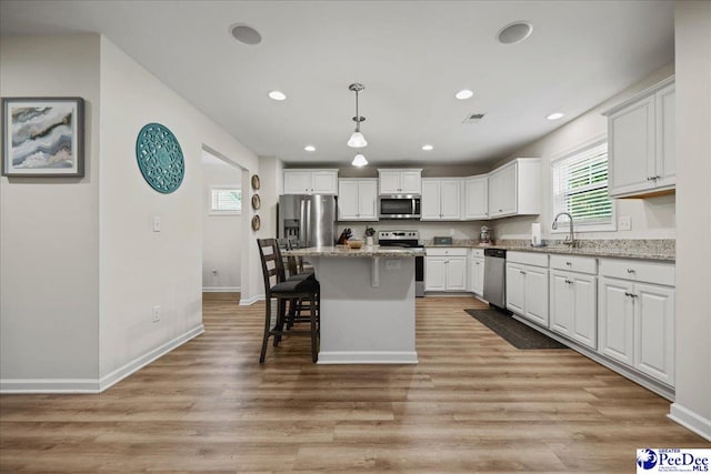 1757 Lake Wateree Dr, Florence, SC 29501 - kitchen with appliances with stainless steel finishes, white cabinets, a kitchen bar, recessed lighting, and light wood-style floors