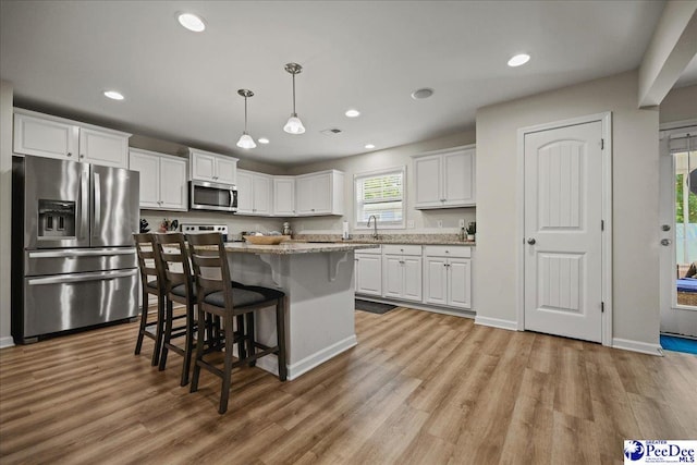 1757 Lake Wateree Dr, Florence, SC 29501 - kitchen with appliances with stainless steel finishes, white cabinetry, a breakfast bar, light wood-style floors, and recessed lighting