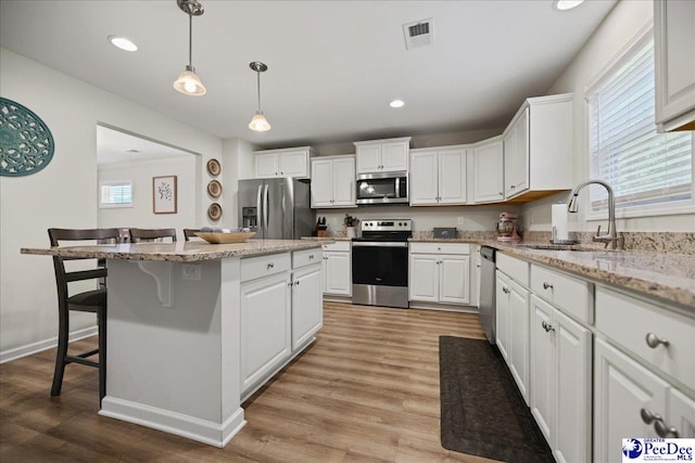 1757 Lake Wateree Dr, Florence, SC 29501 - kitchen featuring appliances with stainless steel finishes, a breakfast bar area, white cabinetry, a center island, and recessed lighting