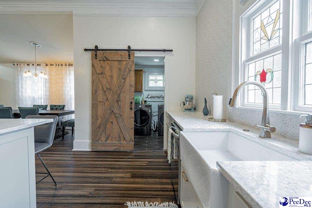 kitchen featuring a sink, light countertops, independent washer and dryer, and crown molding