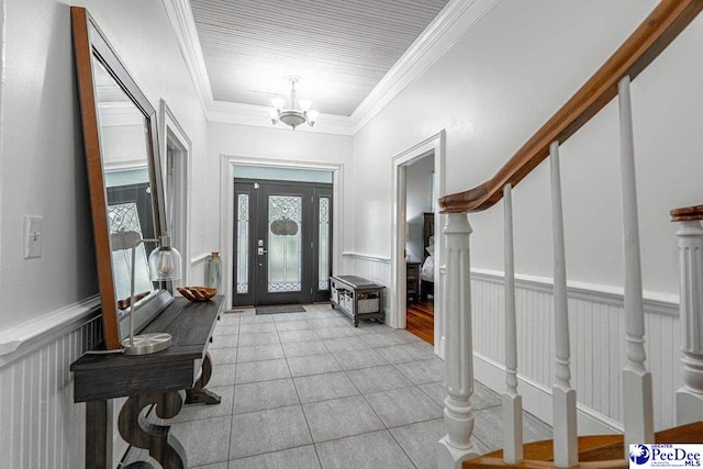 entryway featuring stairs, a notable chandelier, ornamental molding, and wainscoting