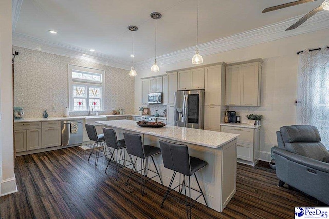 kitchen featuring a breakfast bar, light countertops, a center island, crown molding, and stainless steel appliances