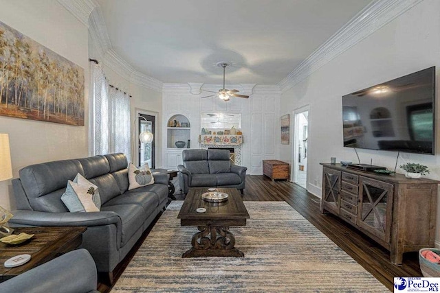 living area with a fireplace, a ceiling fan, crown molding, and wood finished floors